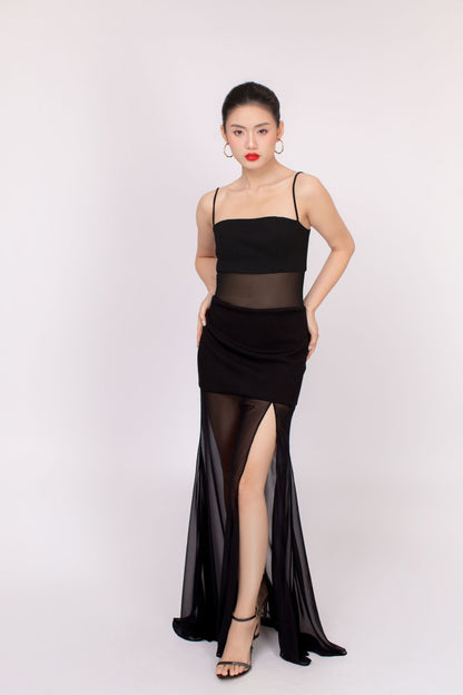 Woman wearing a black dress with sheer panels on a white background