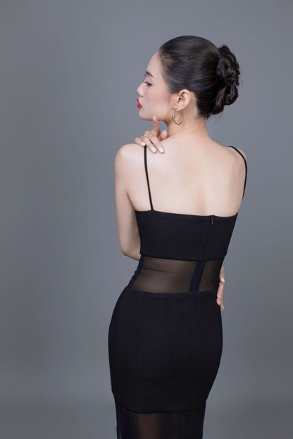 Woman wearing a black dress with sheer panels on a gray background