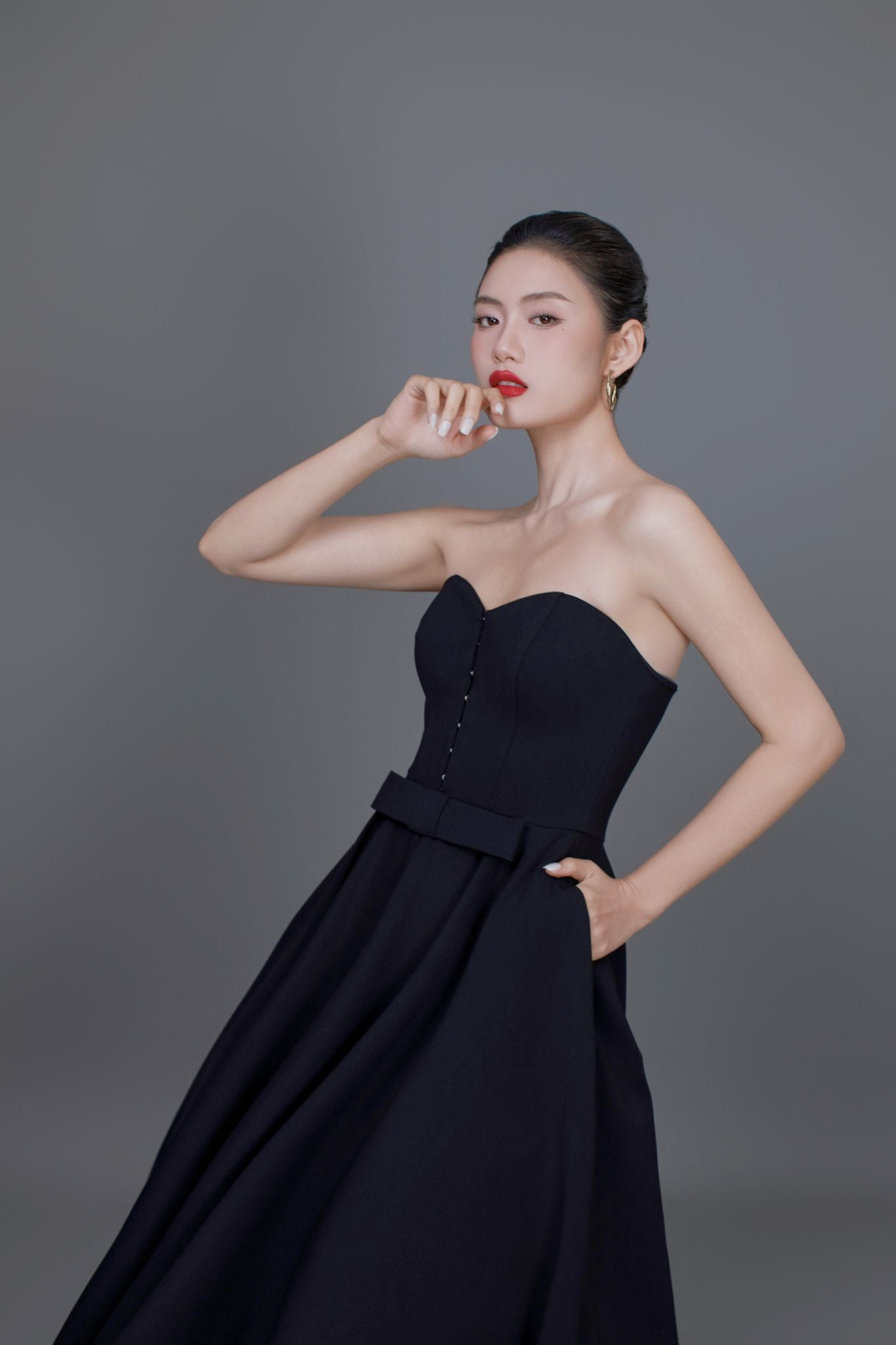 Woman wearing a black strapless dress against a gray background