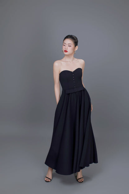 Woman wearing a black strapless dress against a gray background