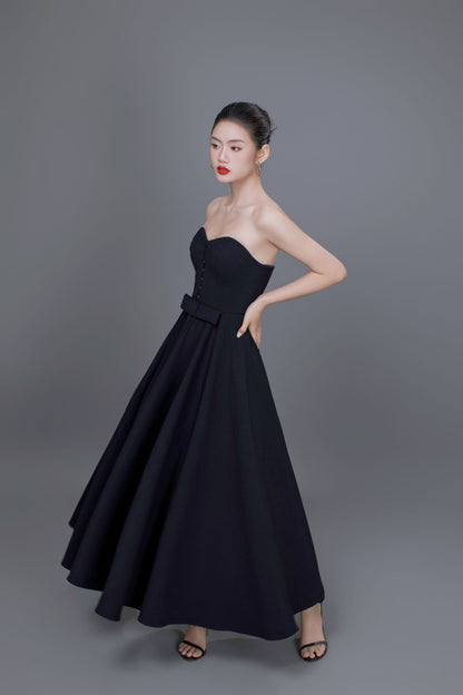 Woman wearing a black strapless gown against a gray background