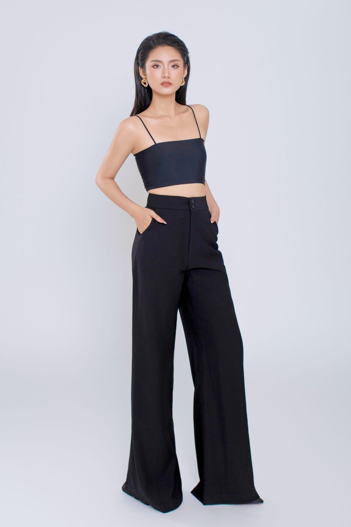 Woman wearing a black top and wide-leg pants on a white background