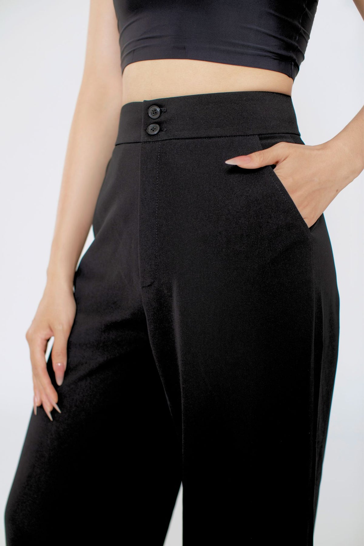 Person wearing black high-waisted pants with a plain background