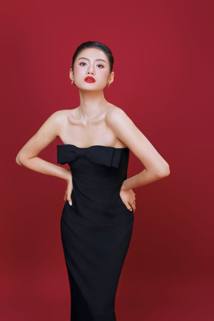 Woman wearing a black strapless dress against a red background