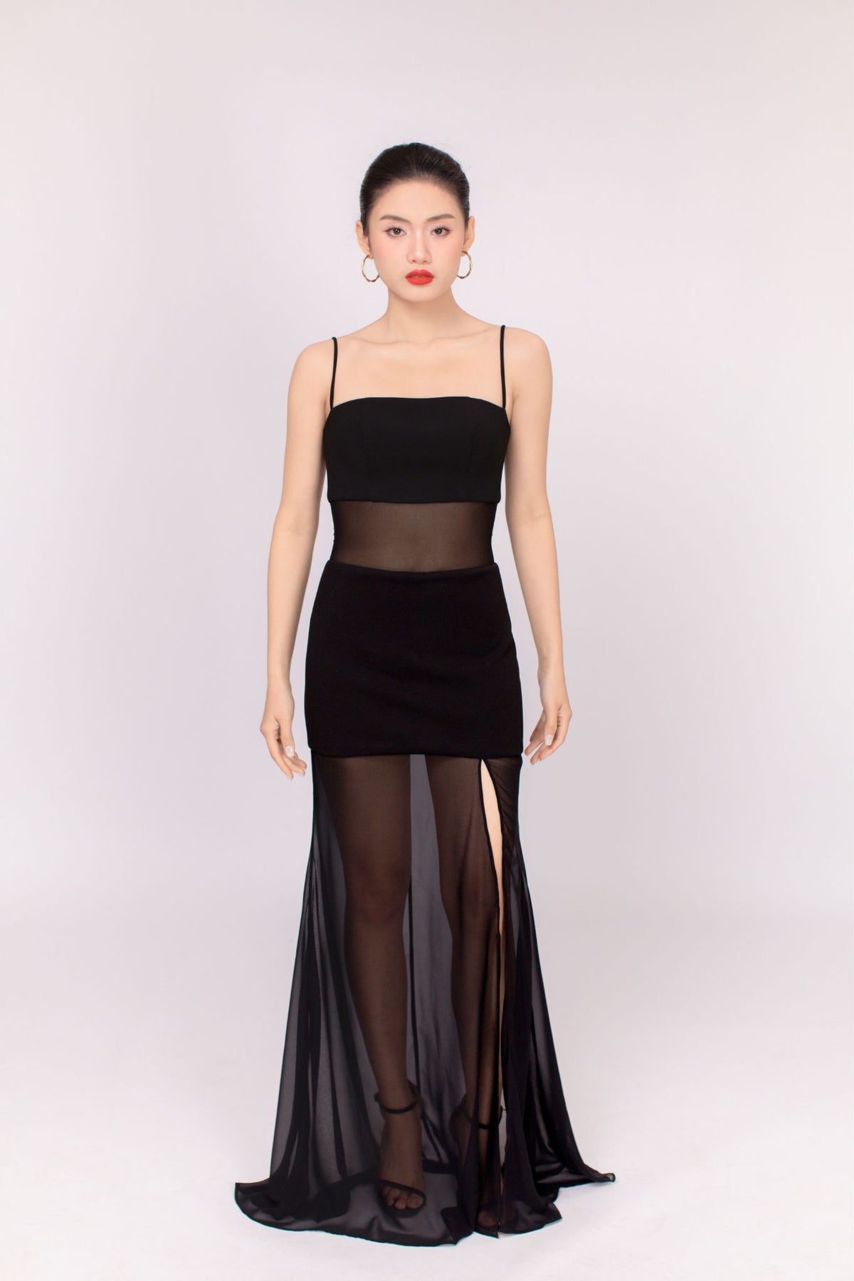 Woman wearing a black dress with sheer panels on a white background